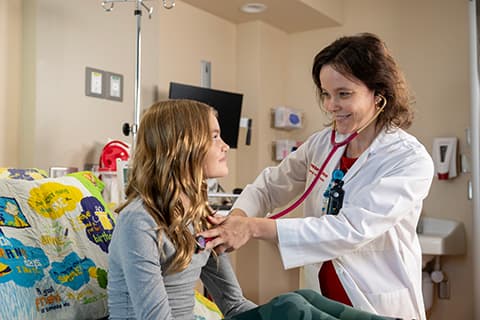 Child in mask holds stuffed animal